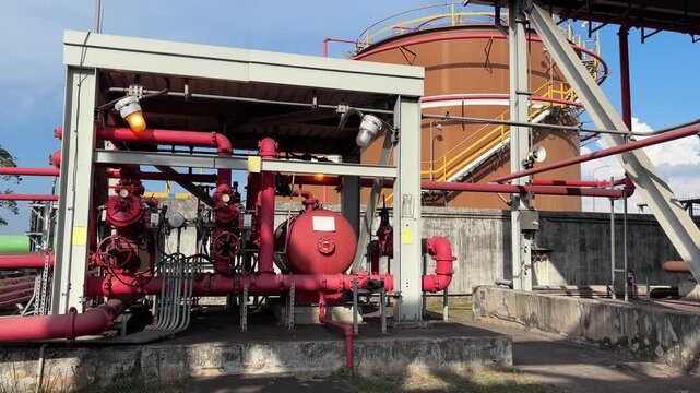 Red fire pumps stand ready near industrial tanks