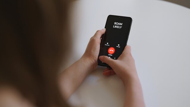 Woman holding smartphone with incoming scam call on screen.