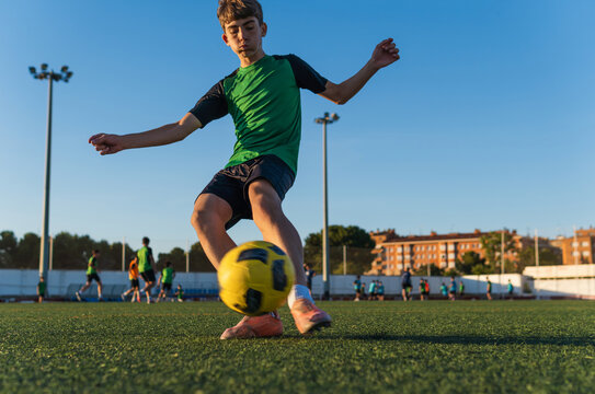 Young soccer player kicking ball on green field