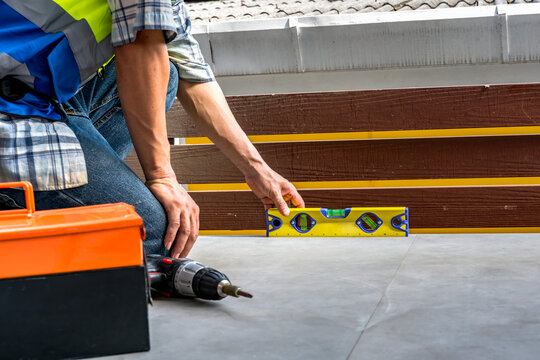 Unknown Asian male construction worker checking accuracy and alignment with a bubble spirit level on floor structure before installation or repair