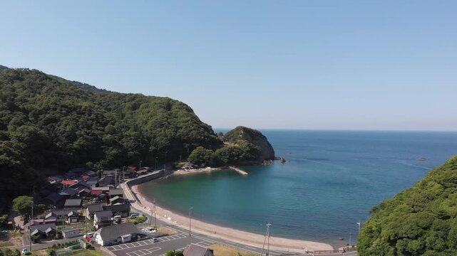 Aerial drone view tracking forward over the scenic Tomari Beach and the peaceful bay in Ine, Kyoto, Japan