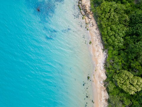 Top Down Aerial View of Turquoise Sea, Rocky Sandy Beach and Forest