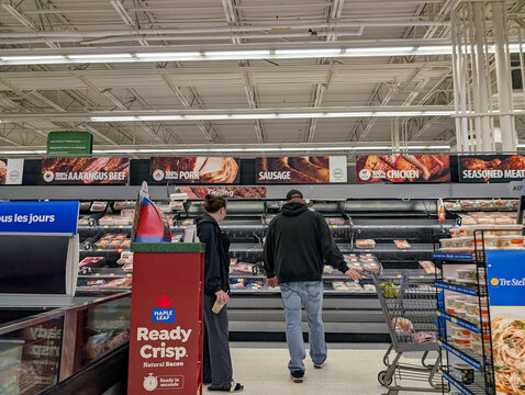 Campbellton, New Brunswick, 06 June 2026 : Shoppers browse refrigerated meat products in a grocery store aisle with various beef, pork, and chicken options.