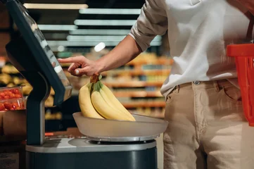 Individual weighing fresh bananas at self-service checkout in grocery store, showcasing modern shopping experience and healthy food choices © standret