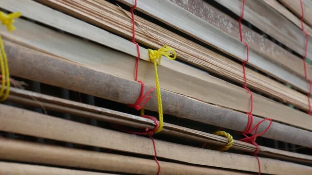 Close Up of Stacked Bamboo Blinds Tied With Colorful Ropes