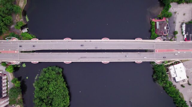 High altitude drone view looking directly down over the Kenneth F Burns bridge on Lake Quinsigamond in Massachusetts. Morning traffic travels in both directions over the bridge.