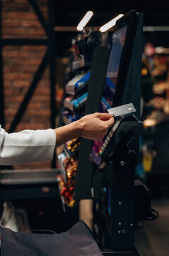 Hand of a customer using a credit card at a self-service checkout kiosk in a modern retail store, showcasing the convenience of digital payment technology
