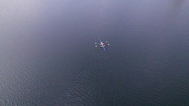 A tandem kayak is rowing in the early morning on Lake Quinsigamon. The kayak approaches the Kenneth F Burns bridge.