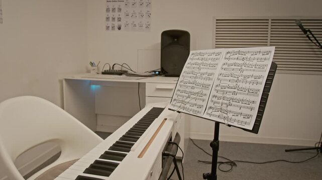 Zoom in shot of digital piano with sheet music standing in empty home studio. Footage for promoting online music lessons, piano tutorials, or creative education programs