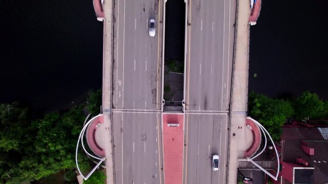 Bird's eye view traveling directly over the two sided Kenneth F Burns bridge. Early morning traffic speeds in both directions as the camera tracks forward.