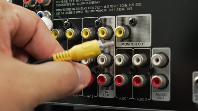 Male hand connects yellow and red RCA cables into the monitor out ports of an o video receiver, emphasizing analog connections and home entertainment setup.