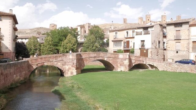 Historic stone bridge spans river in Molina de Aragon with village and castle view