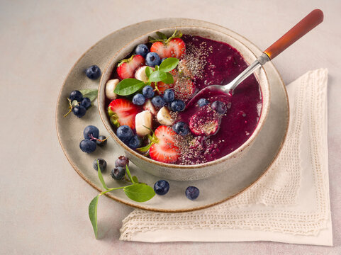 Smoothie bowl made from homegrown organic blueberries topped with strawberyr, banana, and chia seed; copy space