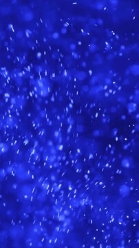 Abstract blue bokeh particles gently floating and shimmering in a dark background