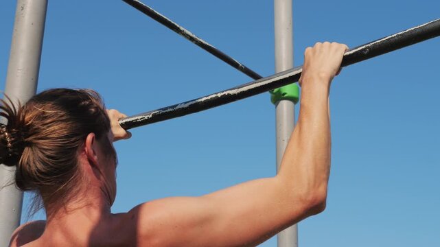 A dedicated fitness enthusiast is performing pullups at an outdoor gym facility