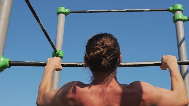 A dedicated fitness enthusiast is performing pullups at an outdoor gym facility