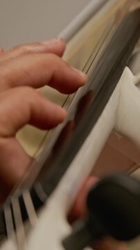 Vertical close-up shot of anonymous musician pressing fingers on strings of electric violin. Clip for music school advertisements or online instrumental learning platforms