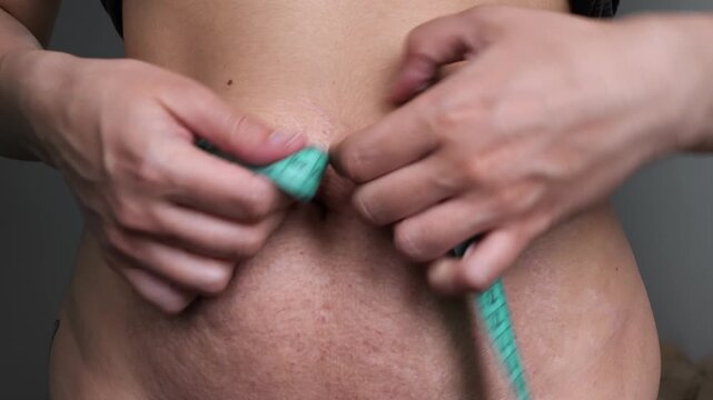 Weight loss journey, woman measuring her waist with a tape measure