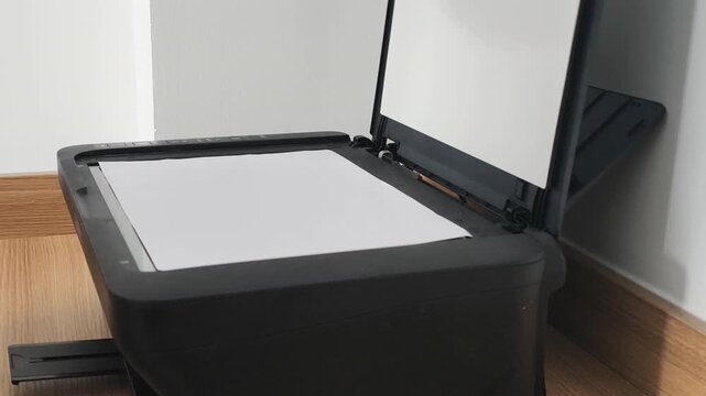 Close up of Closing scanner lid with A4 paper inside in modern office. Human hand is Closing scanner lid with A4 paper inside on office machine glass before copying corporate paper document.