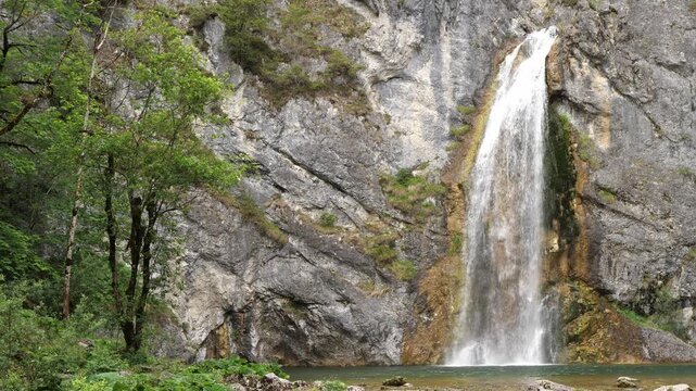 Powerful waterfall, cascade falling down a rocky cliff in the forest