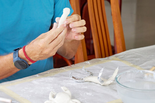 Close up of male hands sculpting clay figure at table. Handmade pottery, creative workshop and ceramics hobby concept.