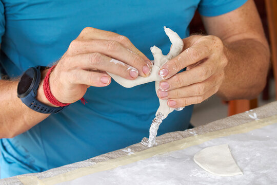 Close up of male hands sculpting clay figure at table. Handmade pottery, creative workshop and ceramics hobby concept.