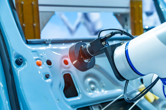 Vision measuring instrument inspecting scanner on robotic arm on background of car manufacturing factory. Automated robot arm assembly line manufacturing. Development and production of automotive tech