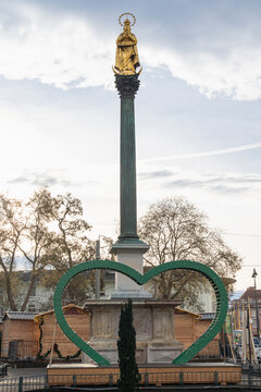 Golden Statue on Tall Column Against Cloudy Sky