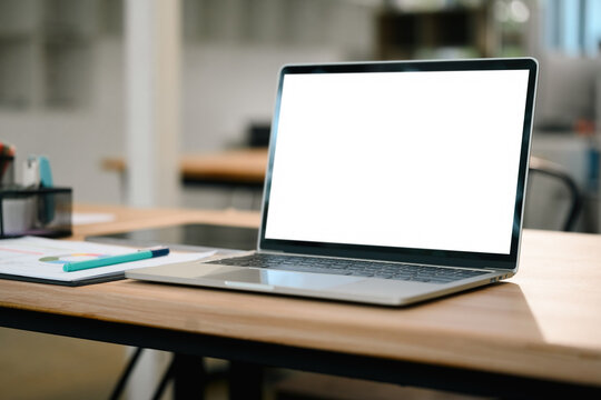 Laptop with Empty White Screen on Wooden Office Desk with Notebook and Pen