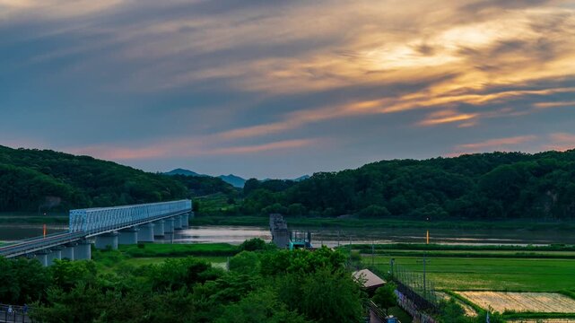 Sunset timelapse of the historic Freedom Bridge over Imjin River at Imjingak DMZ area in Paju, scenic border landscape with railway bridge under moving clouds in South Korea.