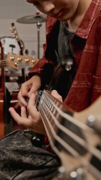 Vertical shot of Caucasian teenager playing electric bass guitar during music lesson. Footage for promoting music schools, youth hobbies, and creative education