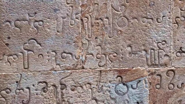 Close view of ancient Georgian inscriptions carved in stone at the historic Monastery of St. Nino in Bodbe, Georgia, revealing intricate cultural heritage.
