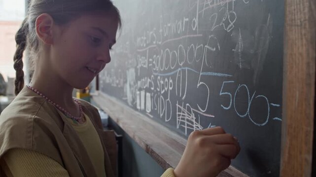 Caucasian girl writing robotics programming code and formulas on blackboard with chalk. Clip is perfect for promoting STEM school programs and science education