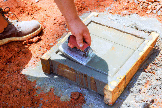 Worker levels concrete in construction site during smooth edge wet cement