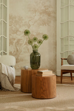Inviting living room interior with contemporary wooden tables, a green glass vase with flowers, and natural decor elements