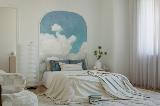 Inviting bedroom with cloud mural feature wall, comfortable bedding, and natural light for a peaceful retreat