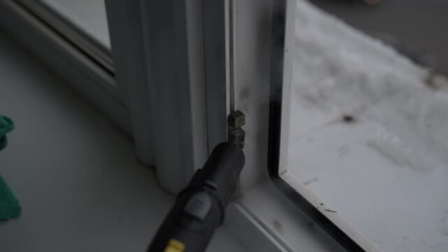 Homemaker cleaner using household steam generator to sanitize and wash dirty plastic window frame, then wiping away moisture and grime with microfiber cloth during general cleaning.