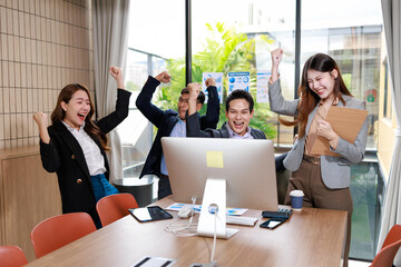 Happy business team celebrating success in a modern office meeting room around a desktop computer