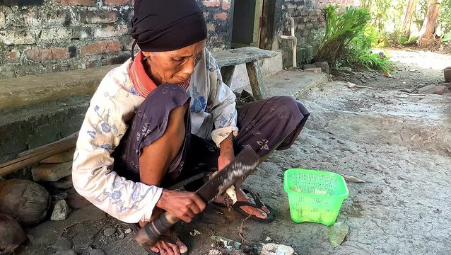 Old Indonesian woman peeling cassava. tropical food.