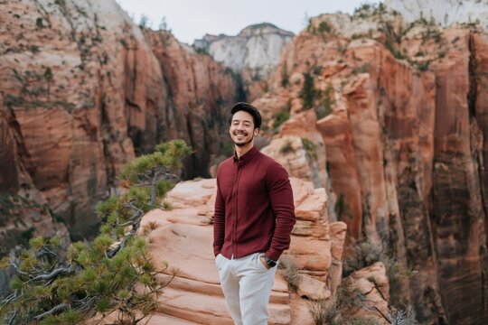 Man standing on narrow rock ledge overlooking canyon during hike