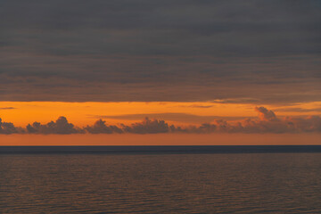 Fototapeta premium Colorful sunset over the sea with dramatic orange after rain clouds.