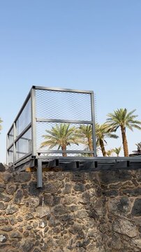 Stone walls and modern equipment at the othman well site in a palm oasis.