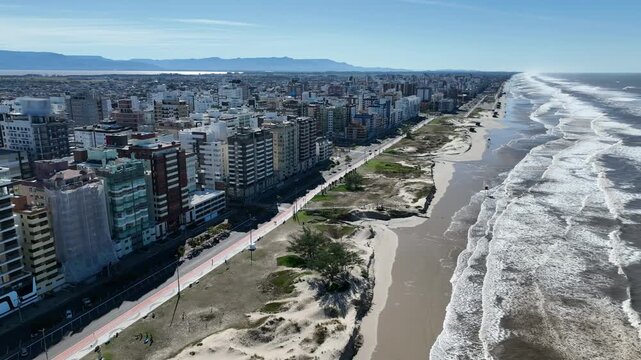 Cap&atilde;o da Canoa beachfront cityscape with high-rise buildings along the sandy coastline under a clear blue sky