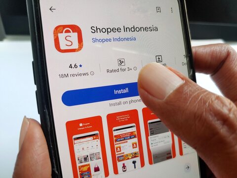 Close-up of a hand holding a smartphone showing the Shopee Indonesia app on the Google Play Store, ready to install.