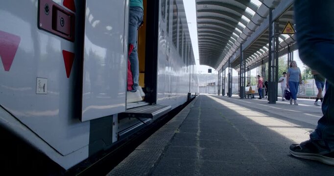 A round station clock hanging under the roof canopy of a railway station.