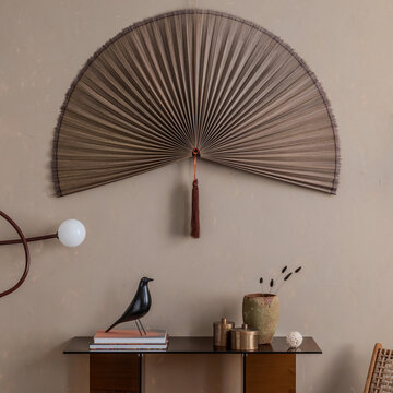 Elegant interior wall decor featuring a decorative fan, console table with a bird sculpture, and various home accents