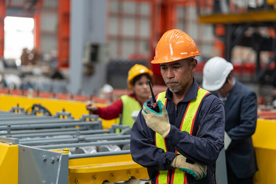 portrait senior male factory worker using a walkie-talkie in manufacturing plant