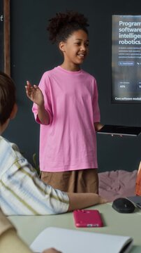 Vertical video of African American girl presenting robotics software project to classmates. Clip is ideal for STEM education marketing and school promotional campaigns