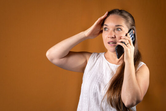 Mujer al tel&eacute;fono con expresi&oacute;n de estar escuchando malas noticias. Concepto de llamadas y comunicaciones.