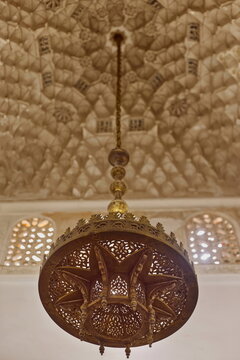 Brass lamp pending from the muqarnas-decorated ceiling above the central area of the ablution chamber, Ben Youssef Madrasa. Marrakesh-Morocco-304